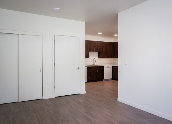 an empty living room and kitchen with white walls and wood flooring