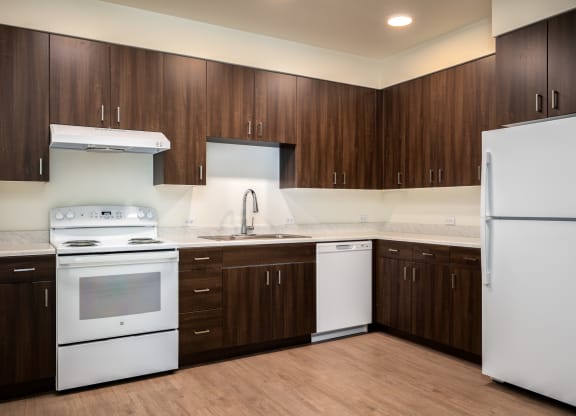 an empty kitchen with white appliances and wooden cabinets