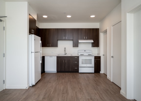 an empty kitchen with white appliances and dark wood cabinets