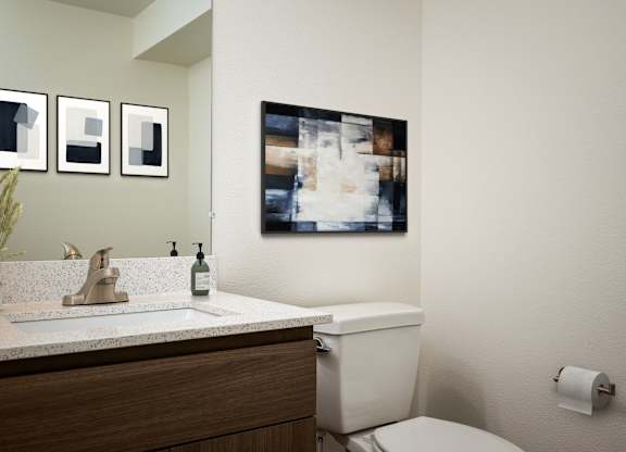 A bathroom with a toilet, sink, and a picture on the wall.