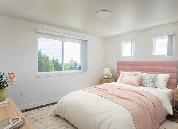 A bedroom with a large bed and a window overlooking trees.