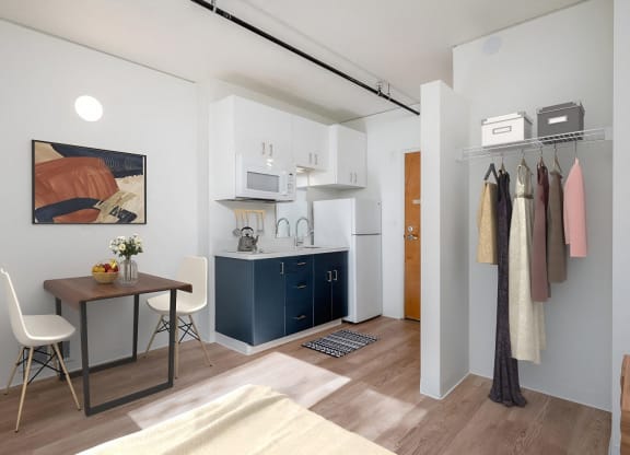 a small room with a desk and a kitchen in it