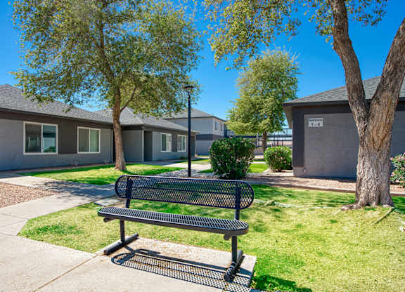 A black bench sits in the grass in front of a building.