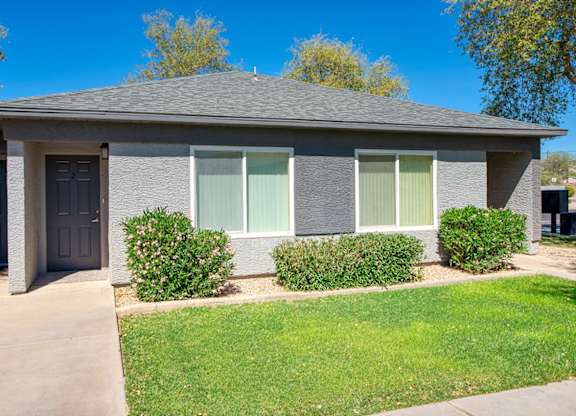 A house with a grey roof and a green lawn in front.
