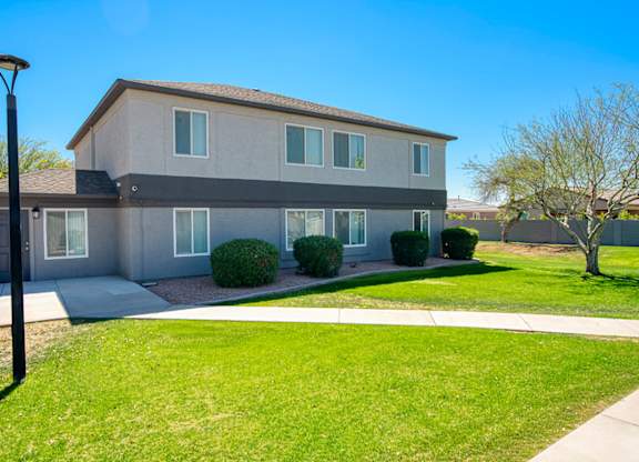 A modern house with a grey and white exterior and a well-maintained lawn.