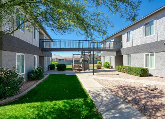 A sunny day at the apartment complex with green grass and trees.