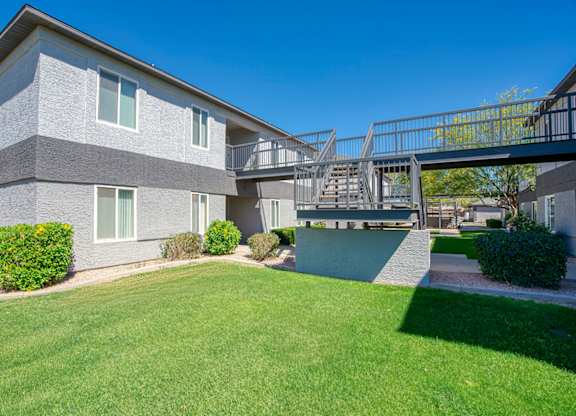 A grey building with a green lawn in front.