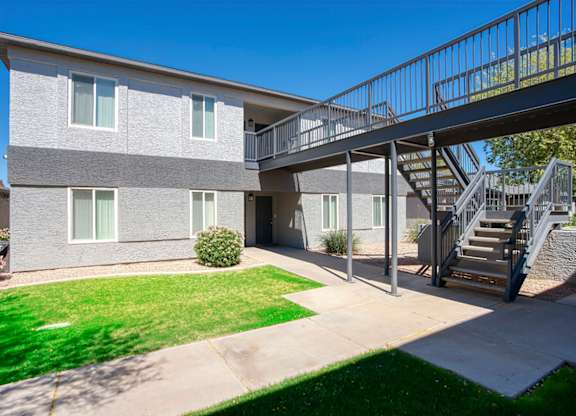 A grey building with a metal staircase leading to the second floor.
