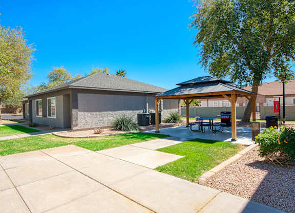 A house with a patio and a tree in front.
