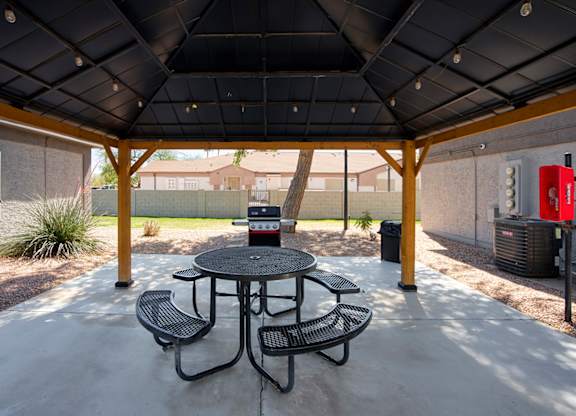 A patio with a table and chairs under a roof.