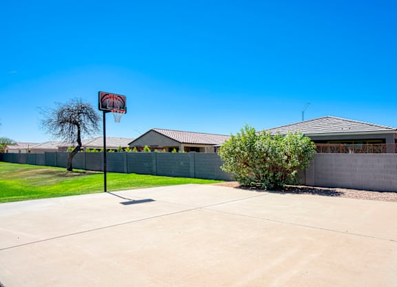 A basketball hoop stands in the middle of a driveway.