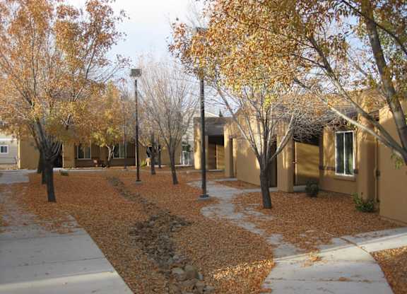 A row of houses with trees in front of them.