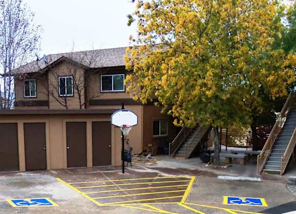 A basketball court with a hoop and two handicap parking spaces.