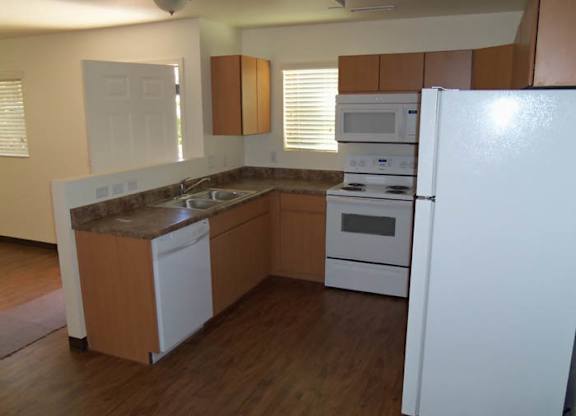 A kitchen with white appliances and wooden cabinets.
