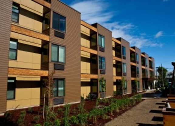 A row of modern apartment buildings with balconies and wooden accents.