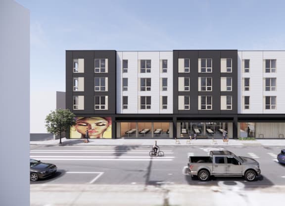 A street view of a building with cars and a mural on the side.