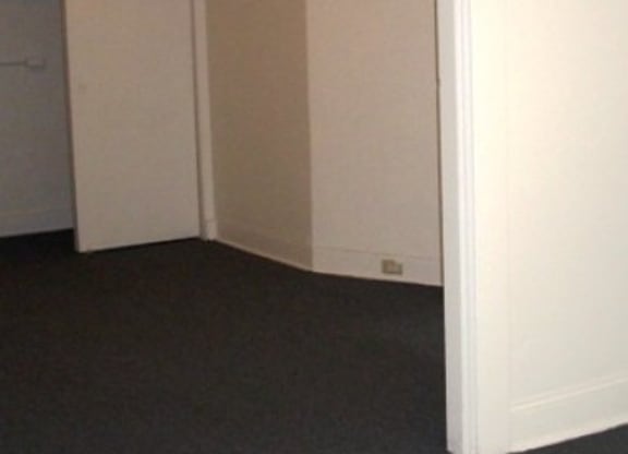 A white door is open to a room with a carpeted floor.