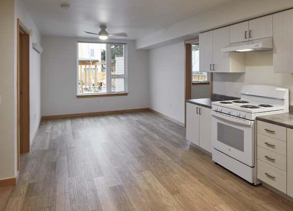 A kitchen with white appliances and wooden floors.