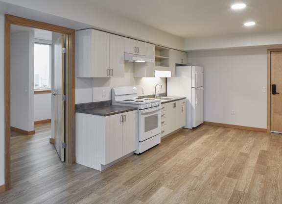 A kitchen with white cabinets and a wooden floor.