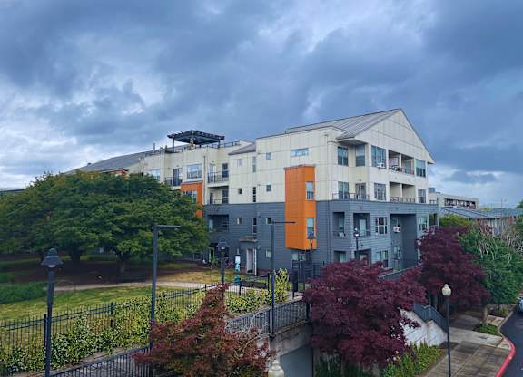 A modern building with a mix of grey and orange accents sits in a residential area.