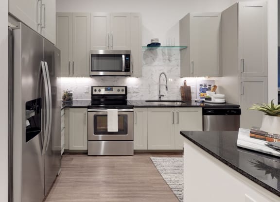 Kitchen with wood cabinets and stainless steel appliances with undermount sink and gooseneck faucet.