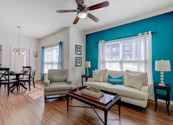 A living room with a white couch, a coffee table, and a dining table at Ethan Pointe Apartments, Greensboro, 27215