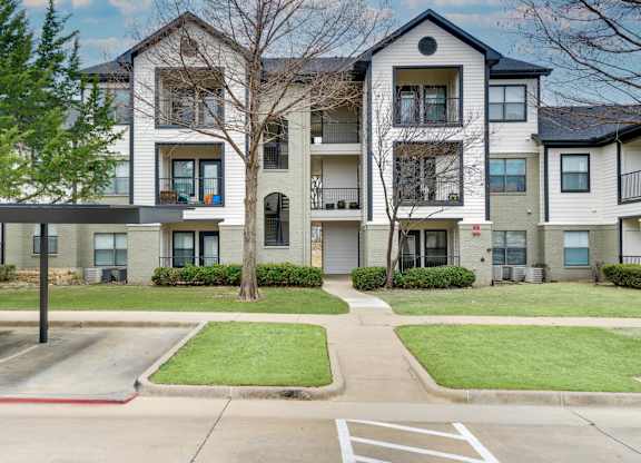 Apartment complex with a parking lot in front.
