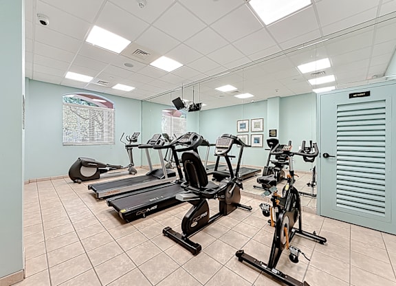 A gym with treadmills, exercise bikes, and a weight bench.