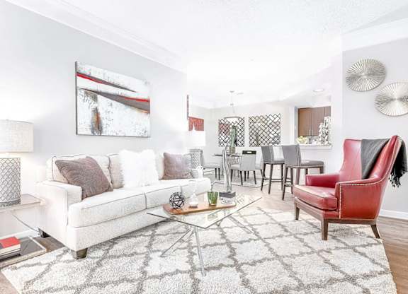 A living room with a white couch, a red chair, and a coffee table.