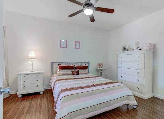 A bedroom with a bed, dresser, and ceiling fan at Ethan Pointe Apartments, North Carolina