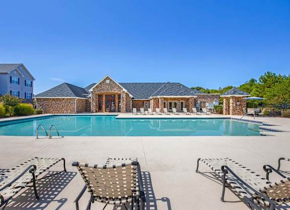 A pool with a stone building in the background at Ethan Pointe Apartments, Greensboro, NC, 27215