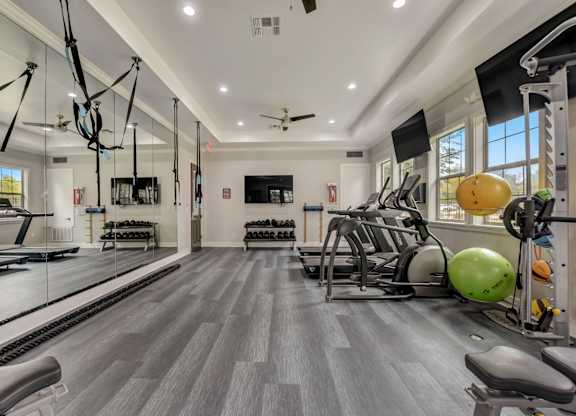 A spacious gym with a variety of equipment and a ceiling fan.