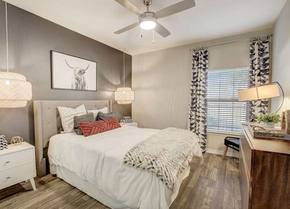 A bedroom with a bed, nightstand, and a ceiling fan.