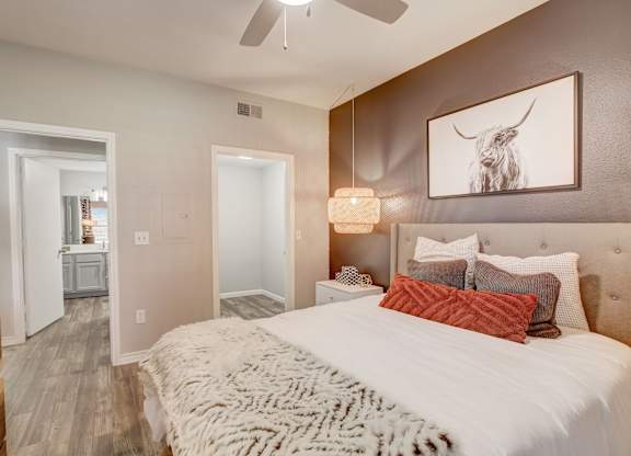 A bedroom with a large bed and a painting of a bull on the wall.