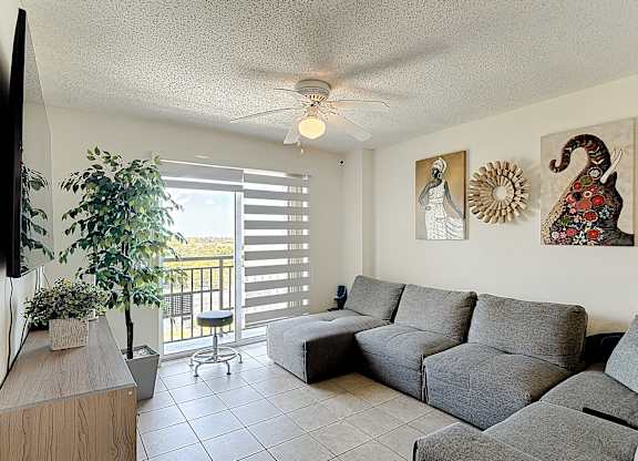 A living room with a grey couch and a ceiling fan.