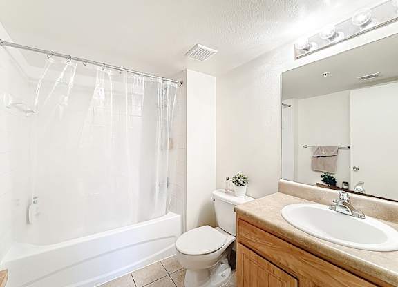 A white bathroom with a toilet, sink, and shower.