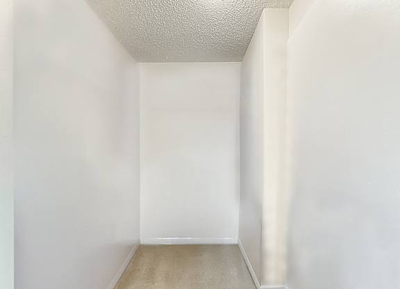 A small, empty room with white walls and a light brown floor.