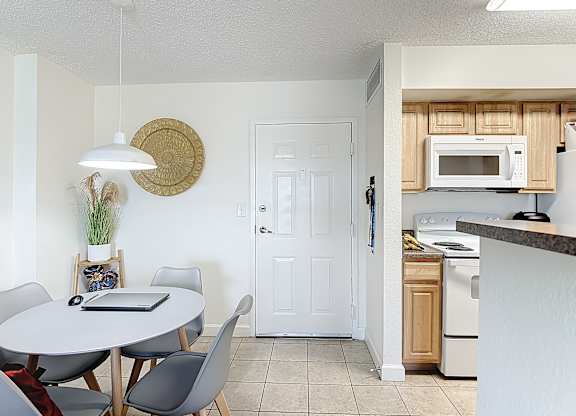 A kitchen with a table and chairs in the foreground and a microwave above the stove in the background.