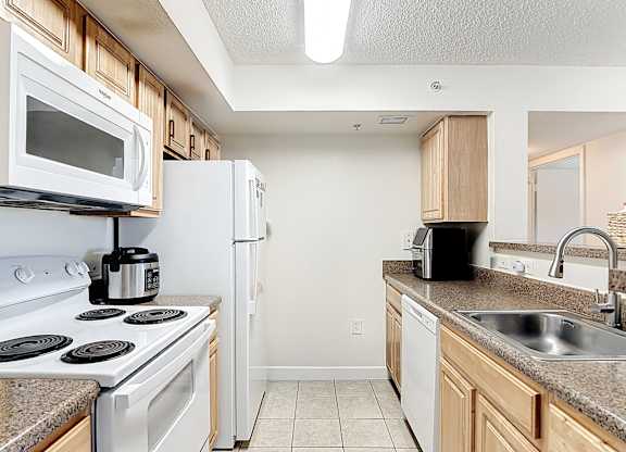 A kitchen with white appliances and wooden cabinets.