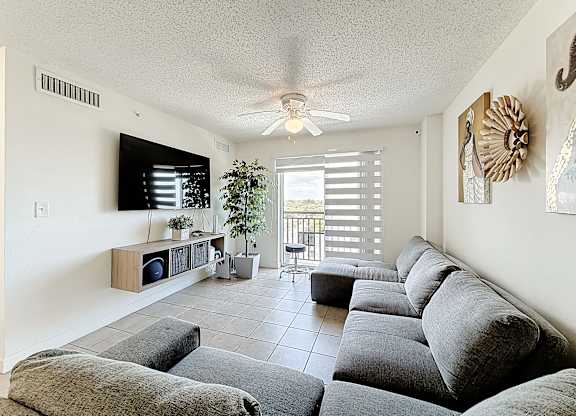 A living room with a grey couch and a ceiling fan.