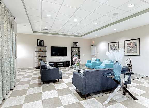 A living room with a checkered floor and a grey couch.