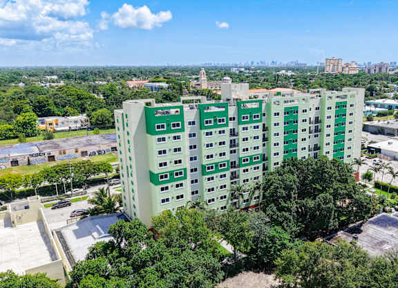 A green and white building with a parking lot in front.