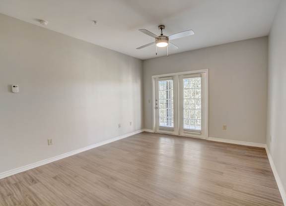 A room with a ceiling fan and a sliding glass door.
