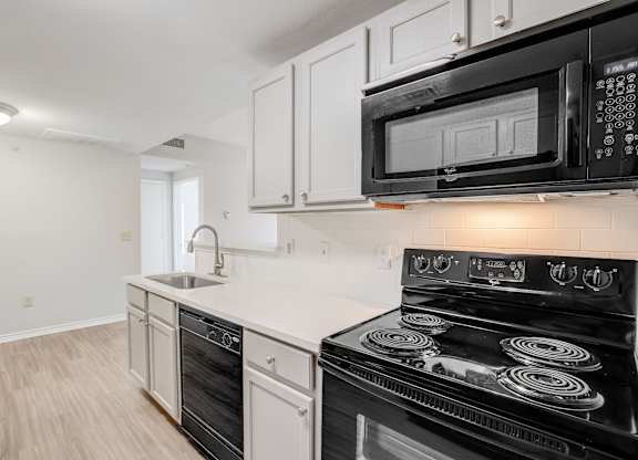 A black stove top oven sits under a microwave in a kitchen.