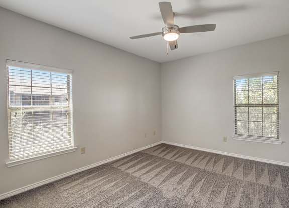 A room with a ceiling fan and carpeted floor.