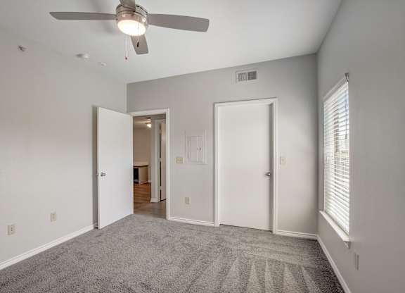 A room with a ceiling fan and carpeted floor.