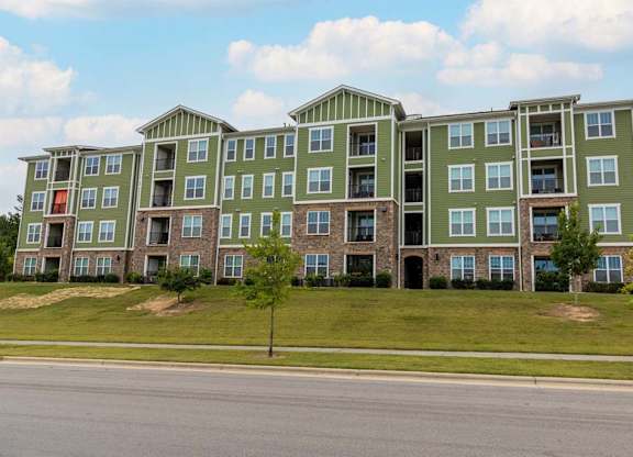 A large green apartment building with a tree in front at Foxwood Apartments, Raleigh-Durham