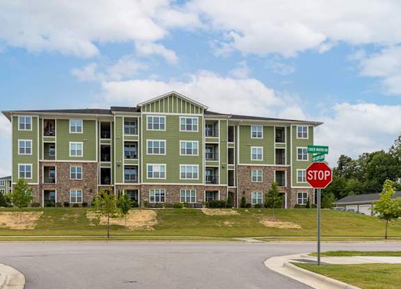 A stop sign is in front of a green apartment building at Foxwood Apartments, Raleigh-Durham, 27616