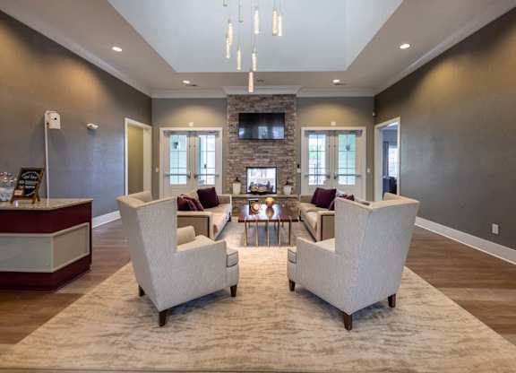 Two white chairs are placed on a rug in a room with a stone fireplace at Foxwood Apartments, Raleigh-Durham, North Carolina