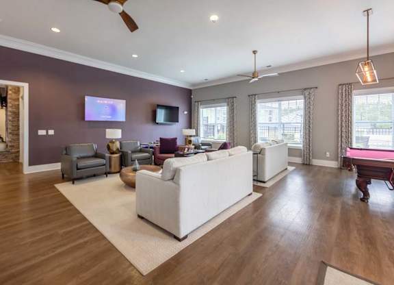 A living room with a white couch and a television on the wall at Foxwood Apartments, Raleigh-Durham, NC
